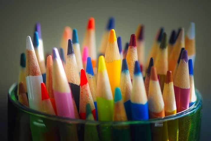 plastic cup full of many coloured pencils