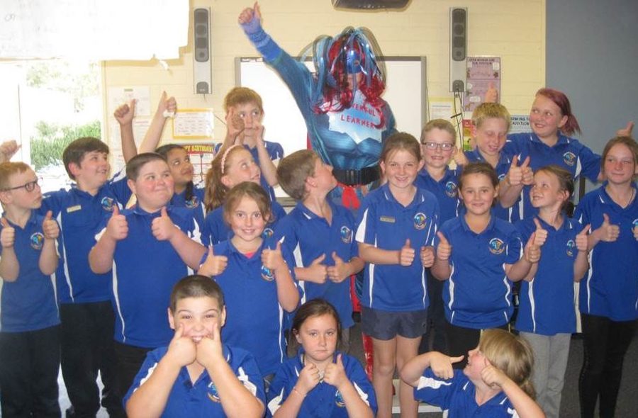 Class of happy students with a teacher dressed as a superhero